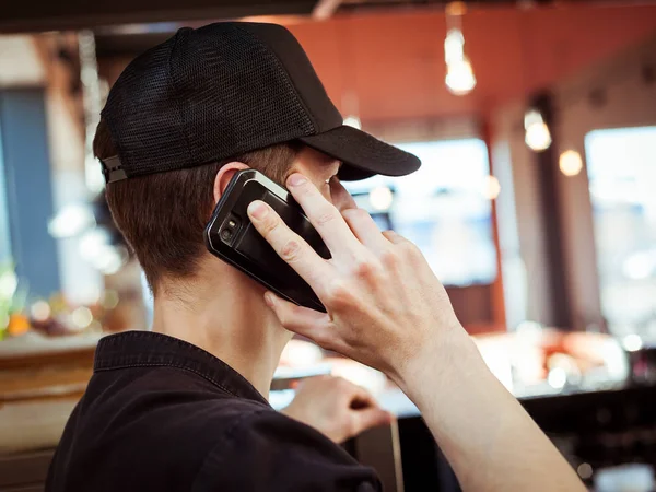 A young man in a cap, talking on a mobile phon