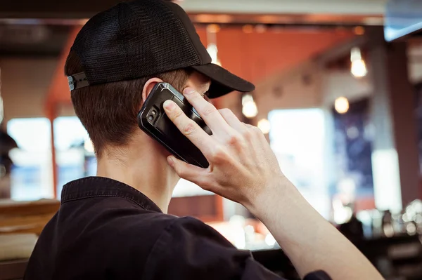 A young man in a cap, talking on a mobile phon
