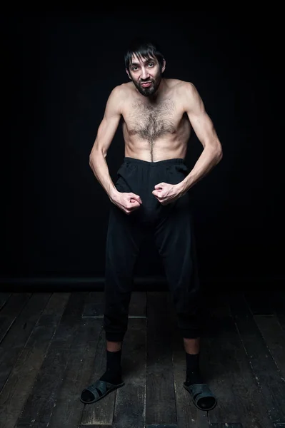 Un joven en sus pantalones sobre un fondo negro — Foto de Stock