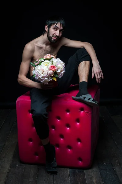 Jovem com flores no fundo preto — Fotografia de Stock