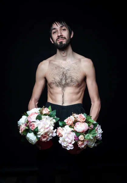 Молодий чоловік з квітами на чорному тлі — стокове фото