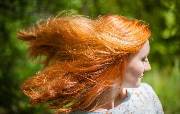 Porträtt av en flicka med rött hår fladdrande i vinden. — Stockfoto