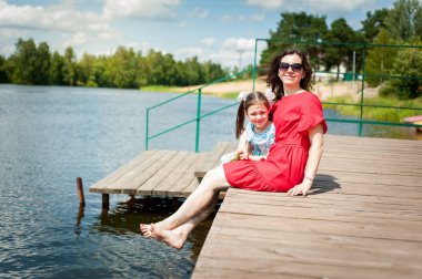 sevimli küçük kız ve annesi bir Güneş çim üzerinde eğlenmek