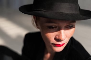 Güneş ışığının arka planında siyah bir şapkayla poz veren kız