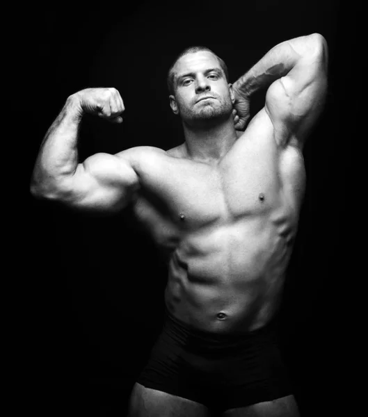 Sports man standing on a black background, doing sport — Stock Photo, Image