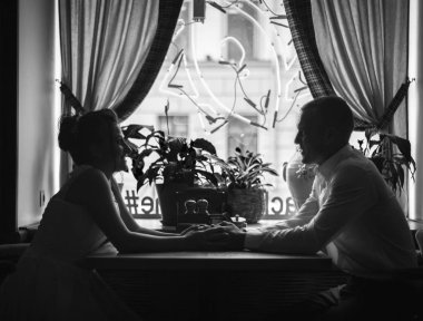 Birbirine aşık bir çift bir kafede el ele tutuşuyor. Ellere odaklan.