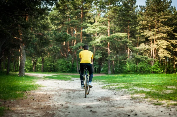 Portrait of a young man moving on a Bicycle. In a public Park, among trees and vegetation.