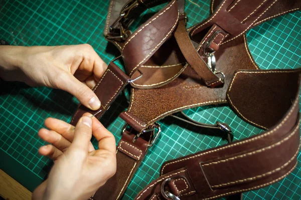 Production of leather products, close up. The view from the side. The master makes a leather product to order.