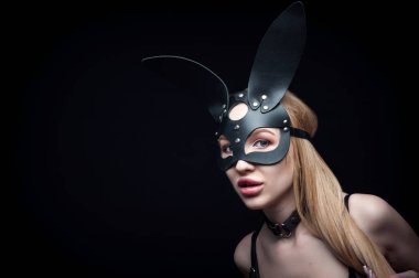 A girl in a black carnival mask. Posing on a black background in the Studio. clipart