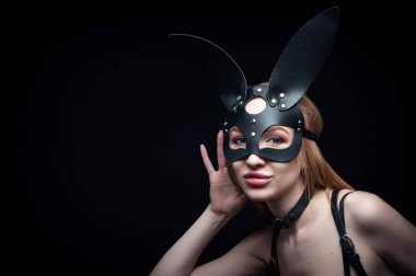 Siyah karnaval maskeli bir kız. Stüdyoda siyah bir arkaplanda poz vermek.