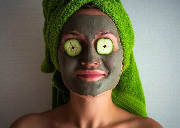 Wanita Muda Cantik Dengan Masker Wajah Wajahnya Memegang Irisan Mentimun — Stok Foto