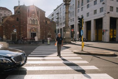 Milan, İtalya - 11 Ağustos 2016: Milano Piazza San Babila 'daki insanlar. Sabah, insanlar işe gidiyor, İtalya 'nın Milano kentindeki San Babila kilisesinin yanından geçiyorlar..