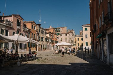 Venedik, İtalya - 13 Ağustos 2016: Turistler güneşli Venedik, İtalya 'nın parlak caddelerinde yürüyorlar.