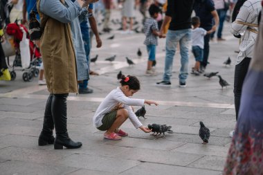 Venedik, İtalya - 13 Ağustos 2016: Turistler Venedik, İtalya 'daki Piazza San Marco' da güvercinleri besliyor.