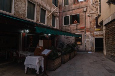 Venedik, İtalya - 14 Ağustos 2016: Kimse bir restoranda masalara oturmaz, bir adam Venedik, İtalya 'da bir restoranın üstündeki daireden dışarı bakar.
