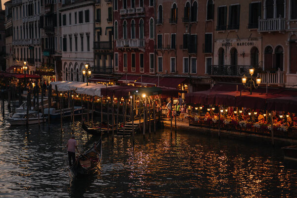 Venice, Italy - August 13, 2016: Restaurants of the Grand Canal promenade in the evening lights in Venice, Italy.