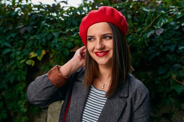 Kırmızı bere saçlarını sabitleme genç bir kadın portresi.