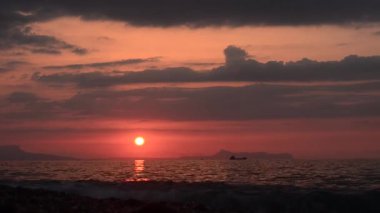dağ ve deniz kıyısına teknede bakan günbatımı