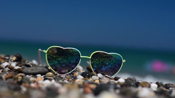 Gafas de sol en la arena. En unas gafas de sol reflejadas mar, olas y cielo . — Vídeo de stock