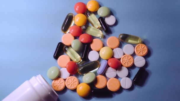Surtido de píldoras de medicamentos farmacéuticos, tabletas y cápsulas y frasco sobre fondo azul — Vídeos de Stock