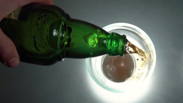 Наливаємо пиво в чашку, рухаємося. Пиво вливається в склянку на текстурованому фоні. Вид зверху на келих пива ізольовано — стокове відео