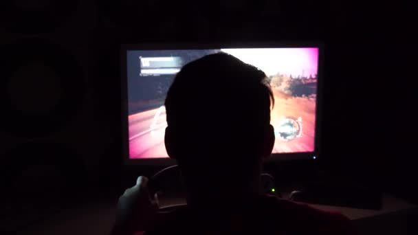 Tecnologia, gioco, intrattenimento e concetto di persone - giovane uomo in cuffia con computer pc giocare auto da corsa video gioco a casa e volante — Video Stock