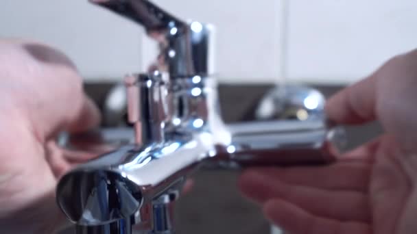 Loodgieter installeren een mixer in een badkamer kraan, hij zit in de badkuip close-up — Stockvideo