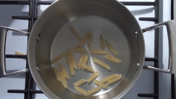 TOP VER câmera lenta: Caindo pilha de cortes de massa, câmera lenta. Pasta penne em água fervente, close-up — Vídeo de Stock