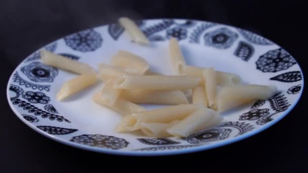 MOCIÓN LENTA: Tortiglioni cocidos caen en el plato completo Penne pasta con salsa de tomate alcance, una rebanada de queso y un poco de menta en la parte superior — Vídeo de stock
