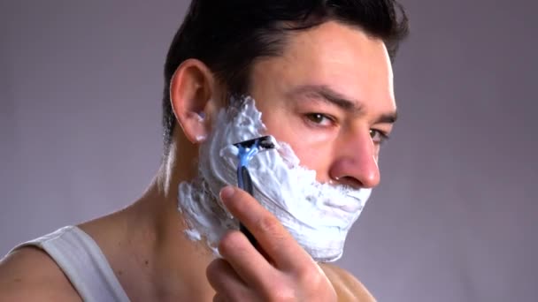 Γέλιο man ξύρισμα το πρόσωπό του, επανδρώνει πρόσωπο με κρέμα ξυρίσματος και ξυράφι κοντά στο πρόσωπο — Αρχείο Βίντεο
