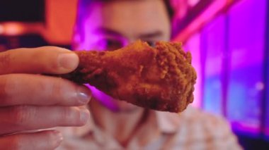 adam yiyor, fast food, tavuk nuggets, kanatları ve patates kızartması iç arka plan ile serin Neon ışıkları mor, mavi ve pembe çift tonlu degradeleri gibi