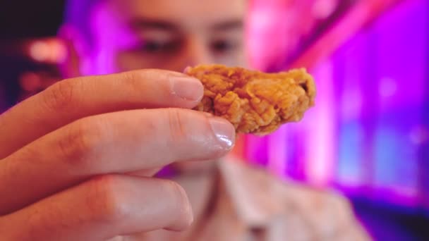 Tipo come pollo frito en un fondo interior de comida rápida con luces de neón fresco como gradientes de duotono púrpura, azul y rosa — Vídeos de Stock