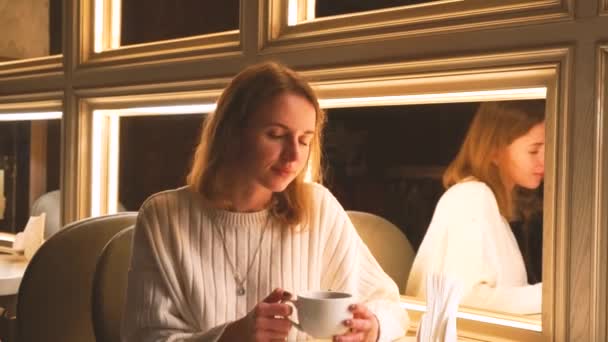 Jovem mulher moderna atraente bebe café aromático em um café — Vídeo de Stock