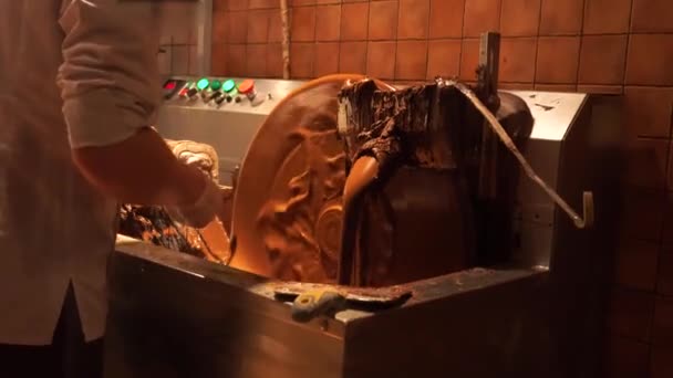 Roeren machine warme chocolademelk. de gesmolten dichte massa draait in een groot vat. Melkchocolade is gegoten uit de metalen kraan in grote portionsmanual productie van A zwarte chocolade, chocolade — Stockvideo