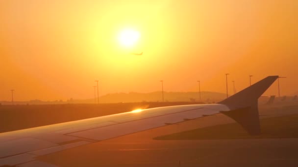 Ala de um avião acima das nuvens sob a luz do pôr do sol. Fundo dourado . — Vídeo de Stock