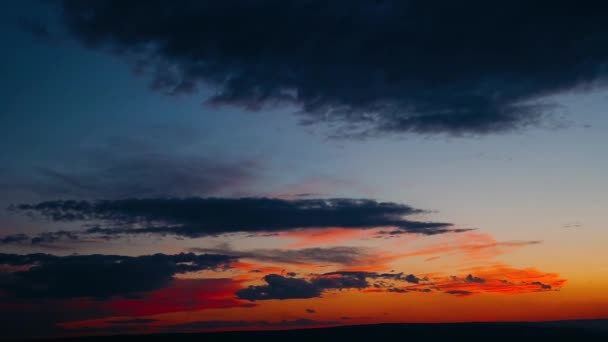 Drammatica nuvole formattazione tempesta in colori vivaci durante il tramonto. Rosso, arancione, viola cielo tramonto con nuvole, veloce lasso di tempo moto. Tramonto nuvoloso sul villaggio e sulle montagne — Video Stock