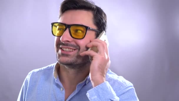 Портрет привлекательного современного молодого кудрявого мужчины в клетчатой рубашке, разговаривающего по мобильному телефону — стоковое видео