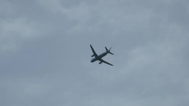 Aereo vola sopra la testa alla partenza attraverso il cielo blu. Entra e foglie girato . — Video Stock