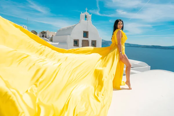 Europa Kreuzfahrt Reise Sommer Urlaub Luxus Touristenziel europäische Frau entspannen in Oia, Santorin, Griechenland in gelbem Kleid Antenne auf dem Dach Stockbild