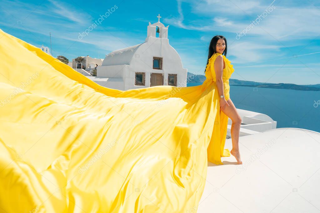 Europe cruise travel summer vacation luxury tourist destination european woman relaxing in Oia, Santorini, Greece in yellow dress aerial on the roof
