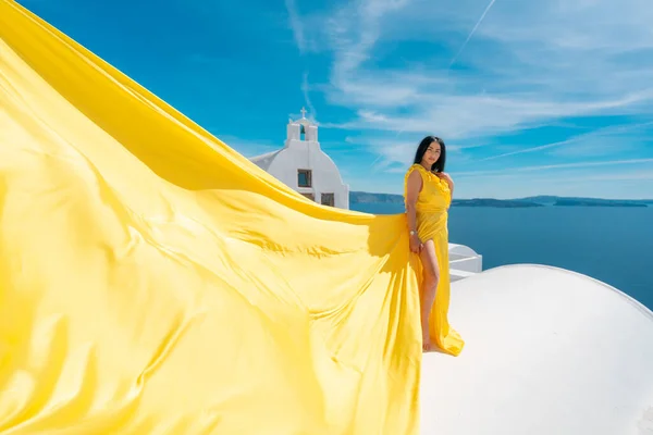 Europa crucero viaje vacaciones de verano destino turístico de lujo mujer europea relajarse en Oia, Santorini, Grecia en vestido amarillo aérea en el techo Imágenes de stock libres de derechos