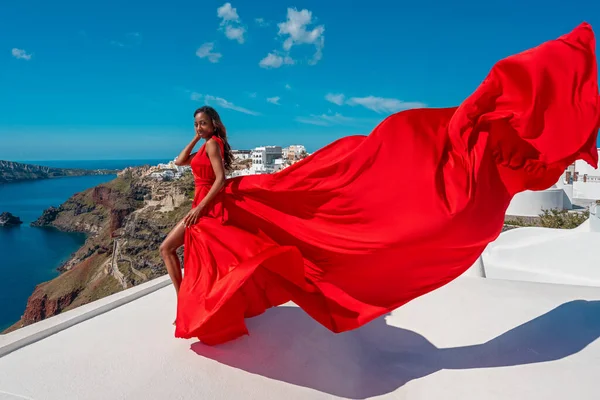 Europa turista viajero mujer en Oia Santorini - Islas griegas vacaciones rojo revoloteando vestido . Fotos de stock libres de derechos