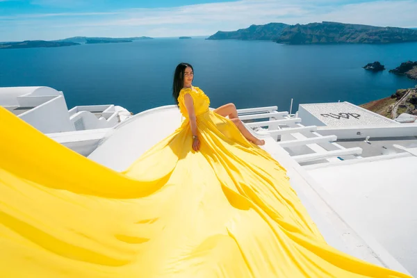 ヨーロッパクルーズ旅行夏休みの高級観光地ヨーロッパの女性は屋根の上に黄色のドレスの空中でOia 、 Santorini 、ギリシャでリラックス ストックフォト