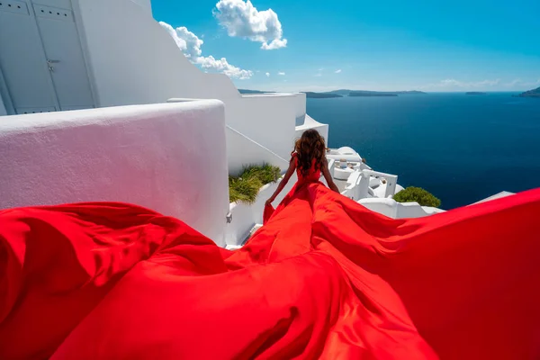 Hermosa mujer correr en rojo vestido de aleteo en Santorini Imagen de archivo