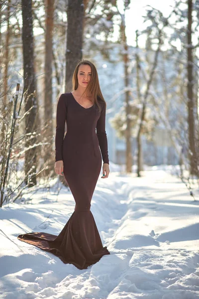 young woman in long dress on snow in winter forest