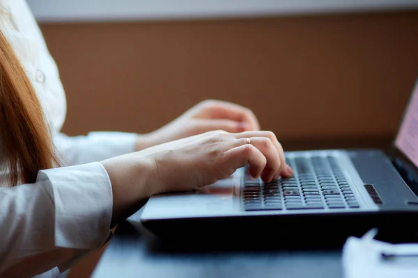 womens hands type a laptop on the keyboard, close-up. Workplace