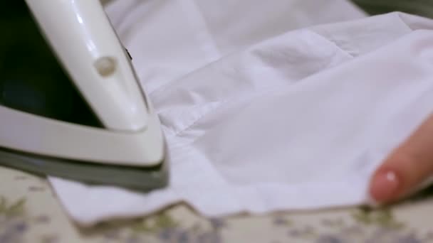 A housewife ironing white T-shirt with electric iron — Stock Footage A housewife ironing white T-shirt with electric iron Stock Footage