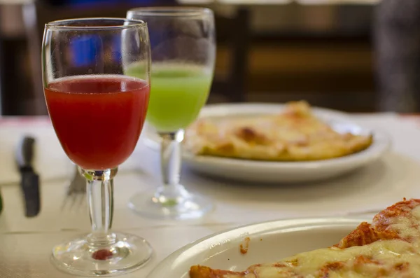 bir dilim pizza ve meyve suyu olan bir kafede masada