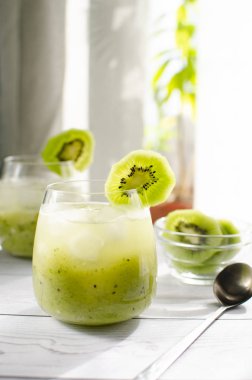 Bir bardak taze sıkılmış kivi suyu üzerinde ahşap bir tablodur