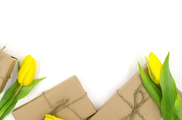 Gift boxes in craft paper with yellow tulips are on a white background